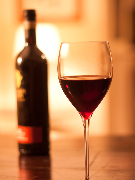 a bottle of red wine in the foreground with a glass of red wine in the front
